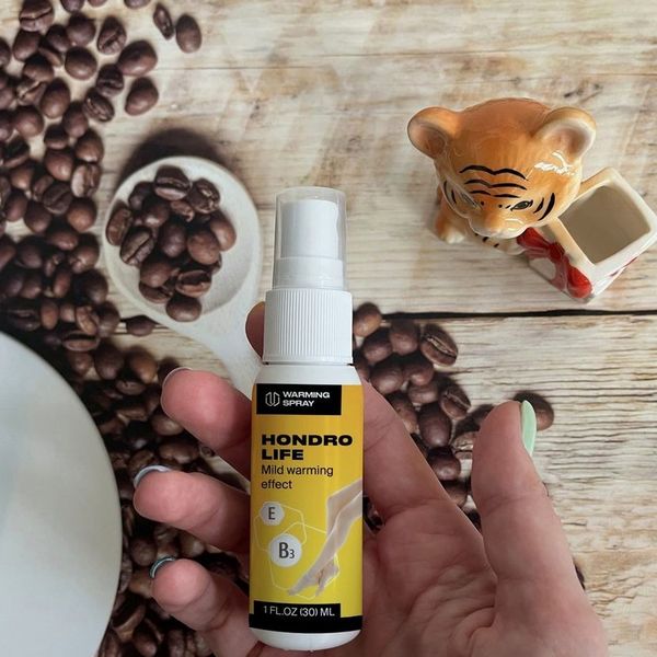 Flacone spray di Hondrolife da 30 ml tenuto in mano con chicchi di caffè sullo sfondo