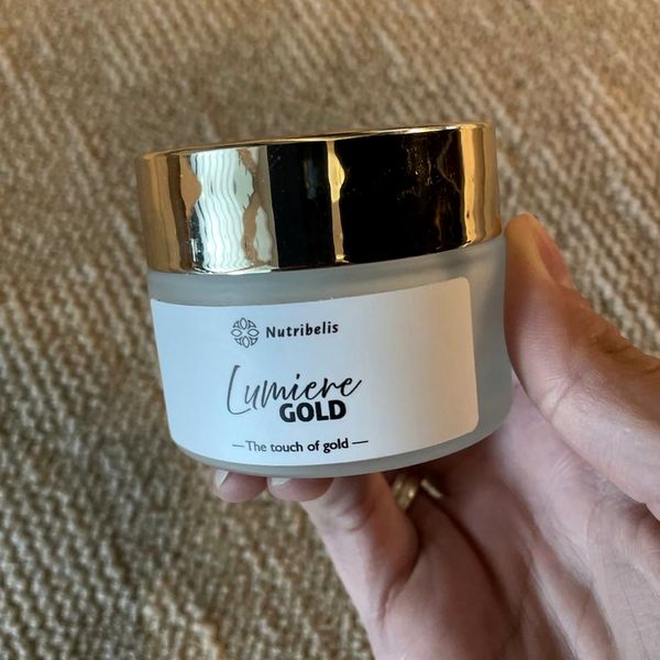 Vasetto di Lumiere Gold con tappo dorato tenuto in mano